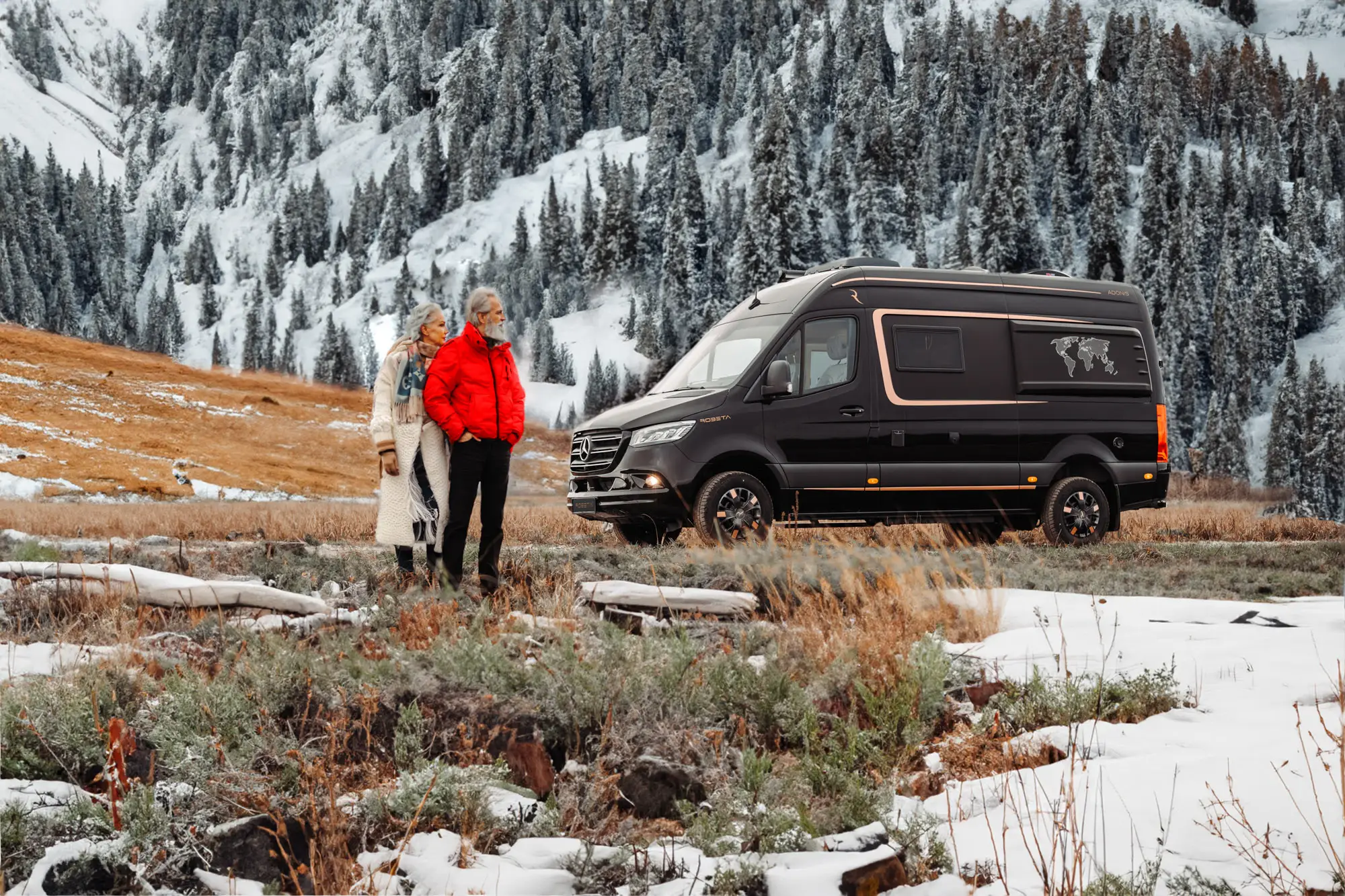 An elderly couple standing together in a snowy mountain landscape next to a black camper van.