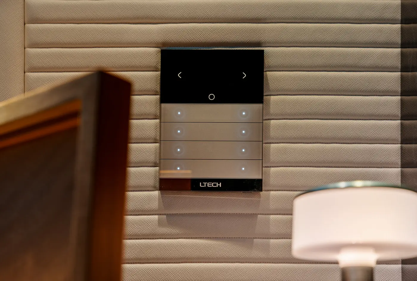 LTECH branded wall-mounted smart light switch panel with six illuminated touch buttons on a textured beige wall.