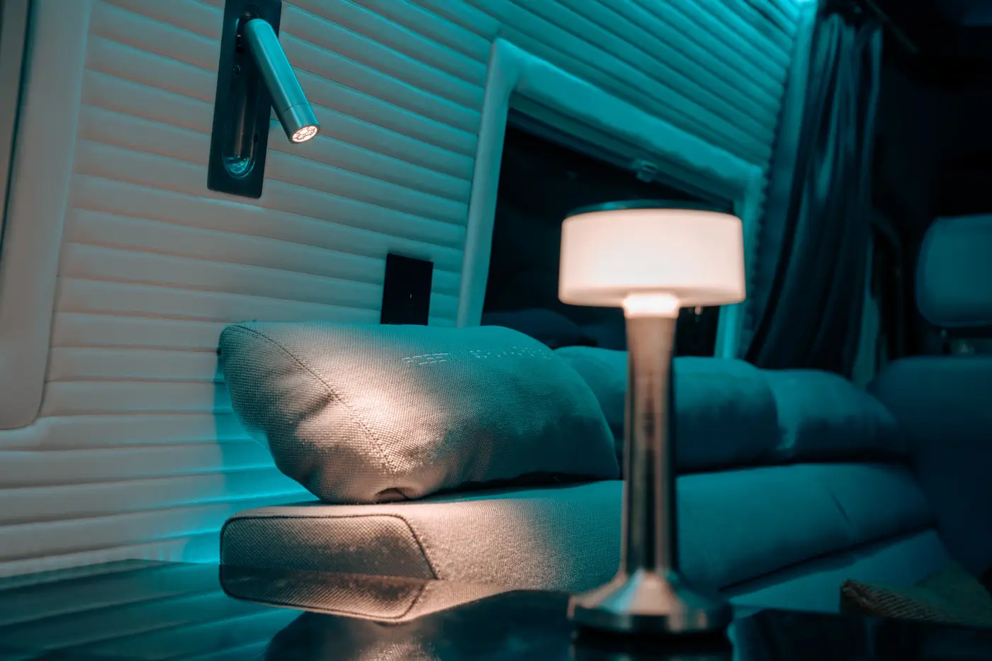 Cozy seating area with a cushioned sofa, decorative pillow, and a modern table lamp emitting warm light.