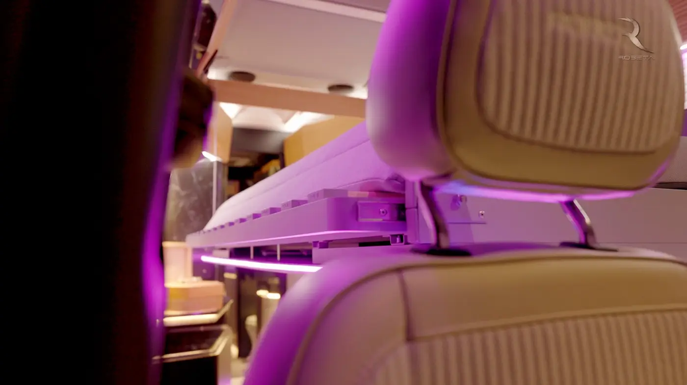 Interior view of a vehicle showing a foldable bed with purple LED lights and beige leather headrest.